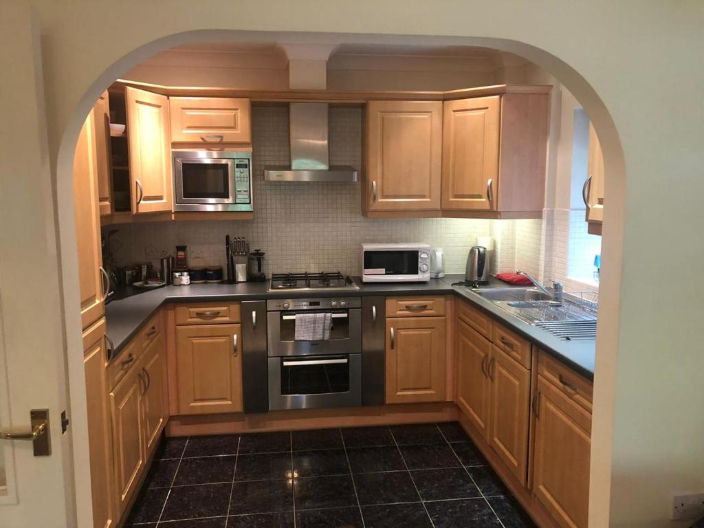 een keuken met houten kasten en een fornuis met oven bij Lovely 2 bedroom 2 baths flat with free parking in Basingstoke