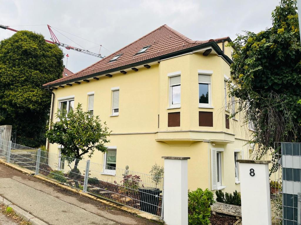 a yellow house with a fence in front of it at Ferienwohnung Bürgel Ebersbach Fils in Ebersbach an der Fils