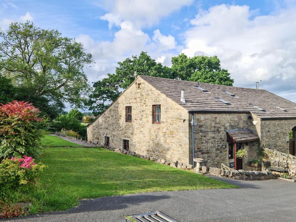 an old stone barn with a grass yard at Hollin Bank Cottage in Salterforth