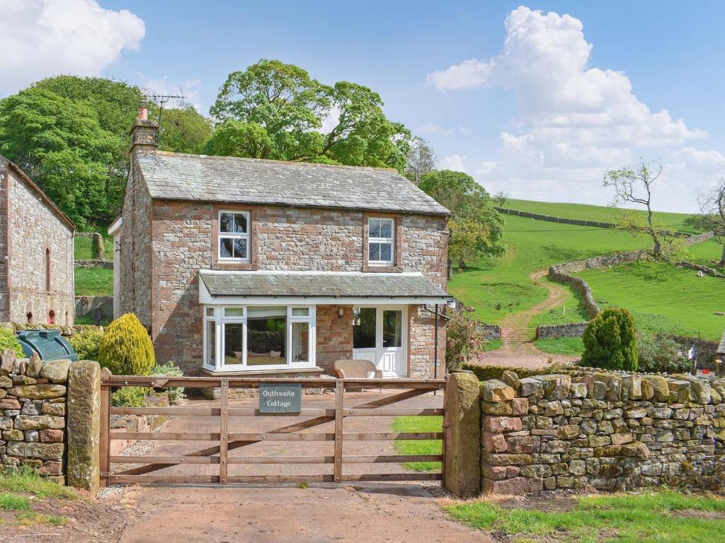 a stone house with a wooden gate and a stone wall at Outhwaite Cottage in Scalehouses