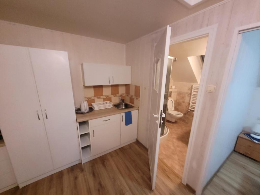 uma pequena cozinha com armários brancos num quarto em Dom gościnny Monika em Pobierowo