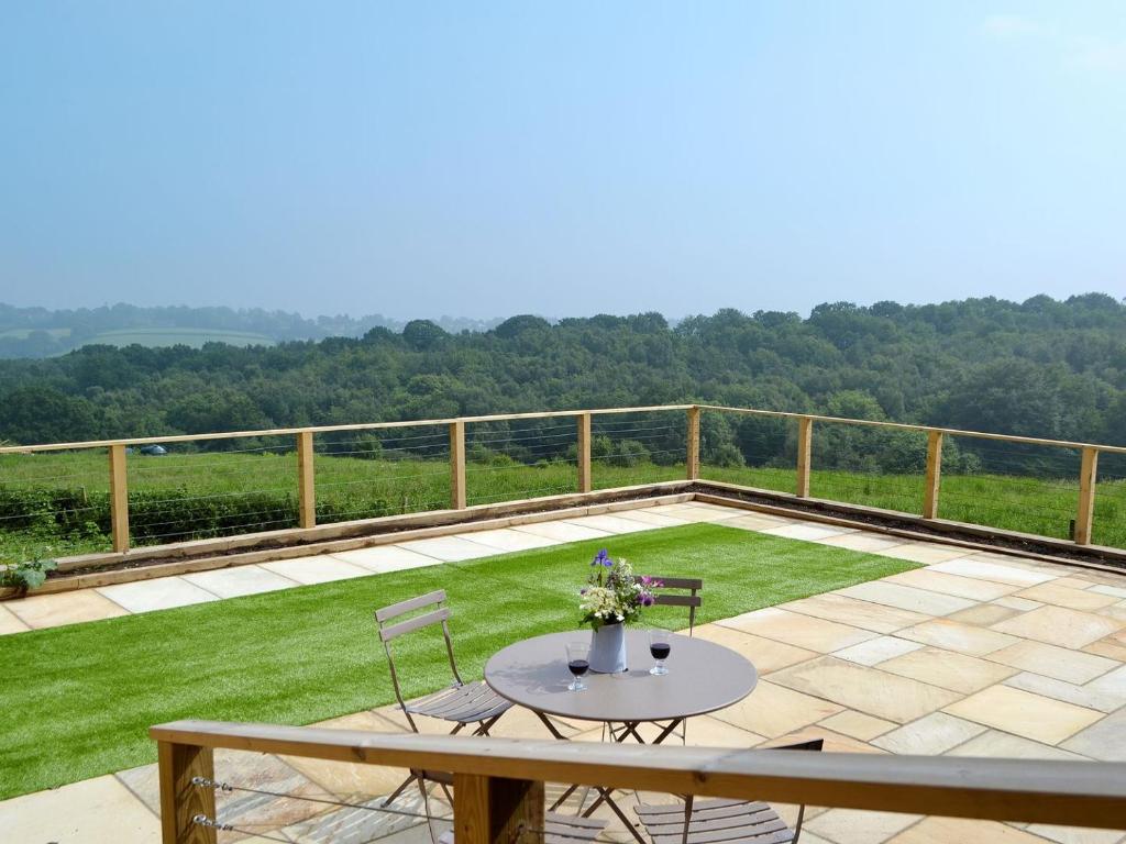 a patio with a table and chairs on top of a field of grass at Poachers View-ukc2488 in Mountfield