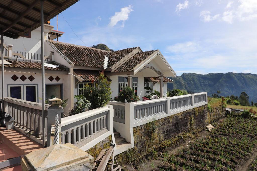 a house with a white fence and mountains in the background at Good Karma Bromo Guesthouse in Bromo