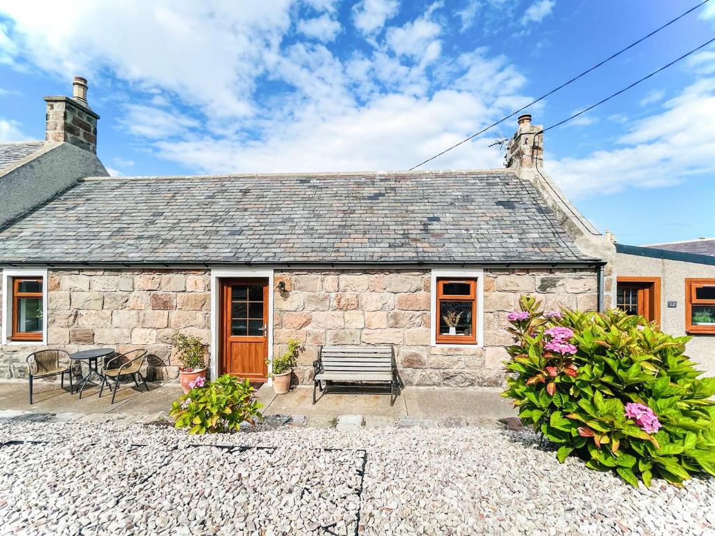 a stone cottage with a bench and a table at Portknockie Escape in Portknockie