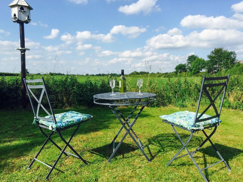 Hoveringham的住宿－Acres View，桌子和两把椅子,上面装有酒杯