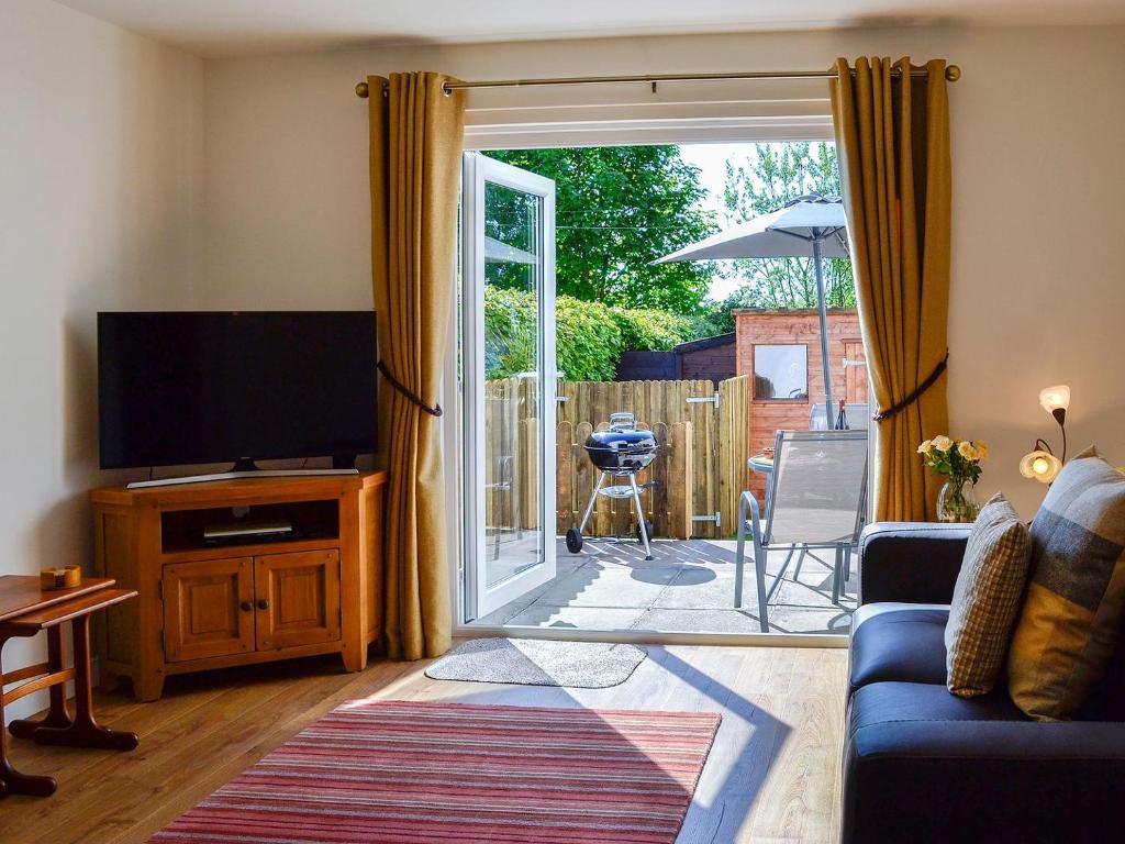 a living room with a tv and a sliding glass door at Little Cottage in Wigtown