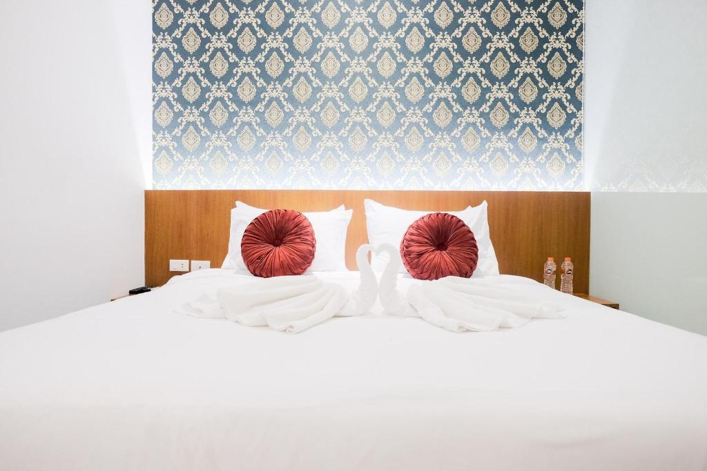 棉蘭的住宿－King's Palace Mitra RedDoorz，两个白色天鹅坐在床上,床上有红色枕头