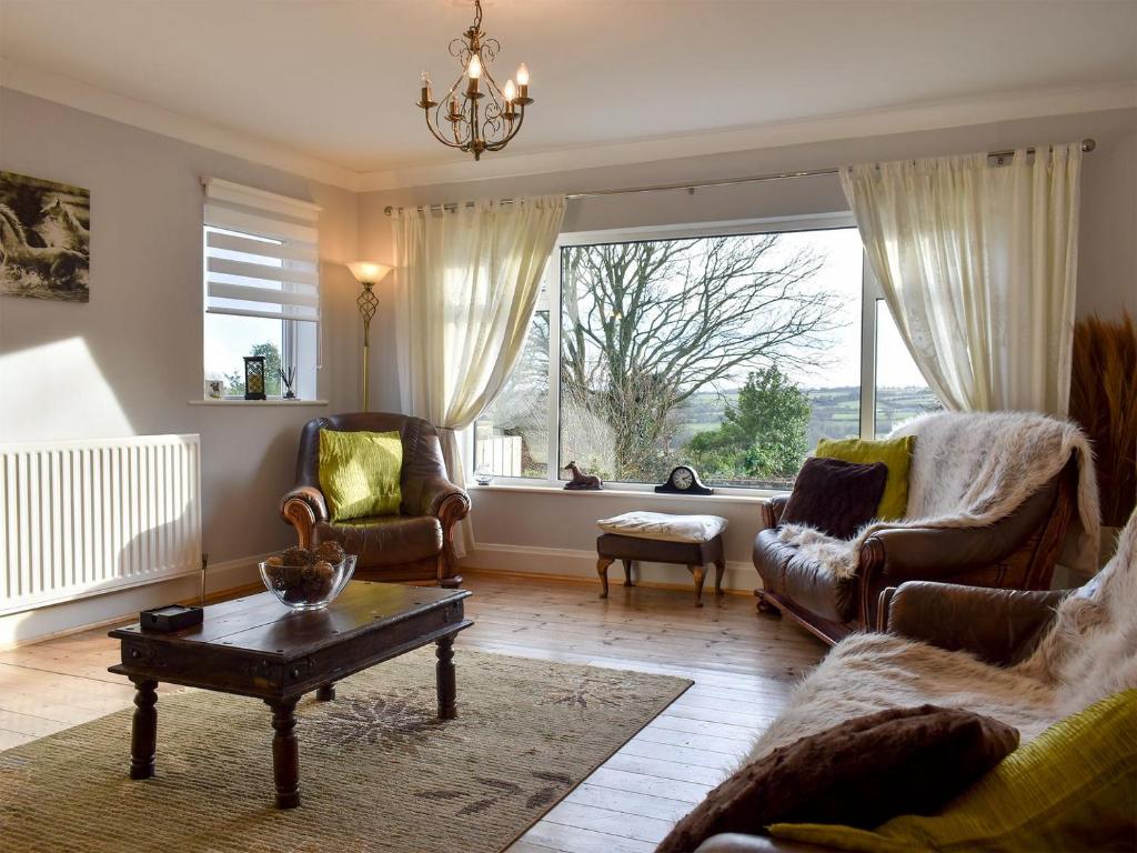 a living room with a couch and chairs and a large window at Cotswolds Cottage in Hamsterley