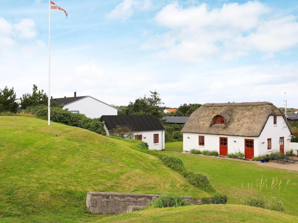 une maison blanche avec un toit de chaume sur une colline verdoyante dans l'établissement 8 person holiday home in Blokhus, à Blokhus