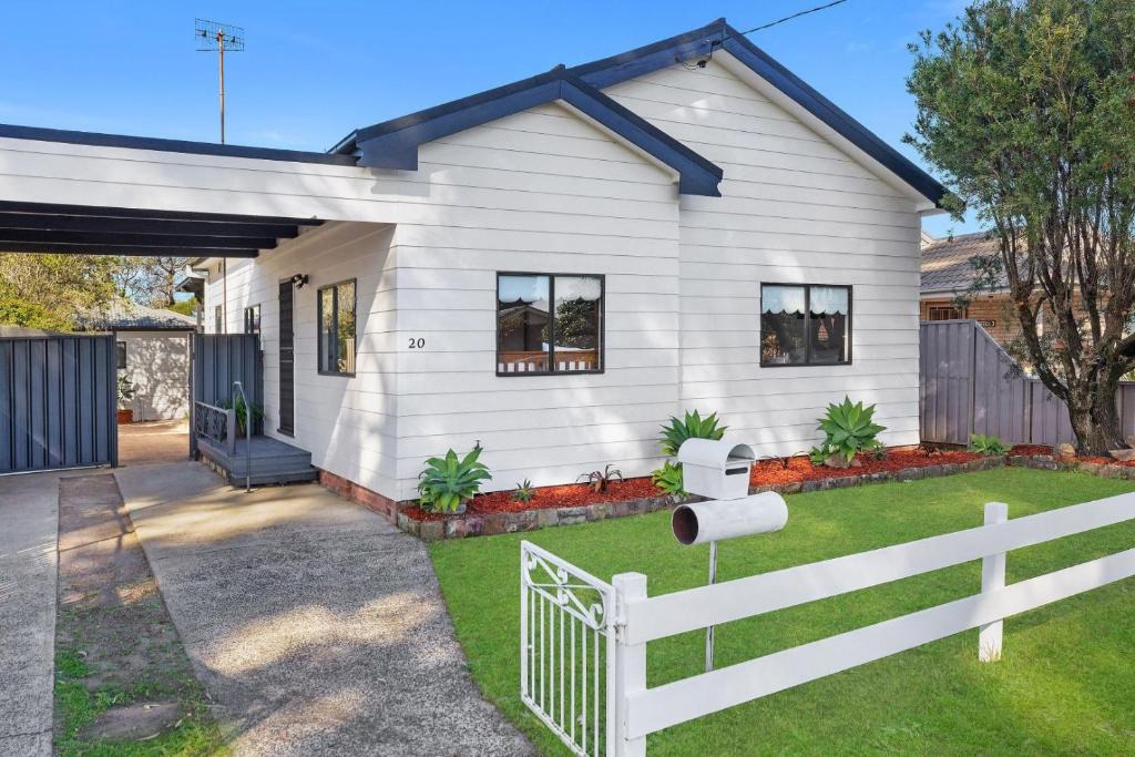 a white house with a fence in front of it at Large Cottage Near Ettalong Centre in Ettalong Beach