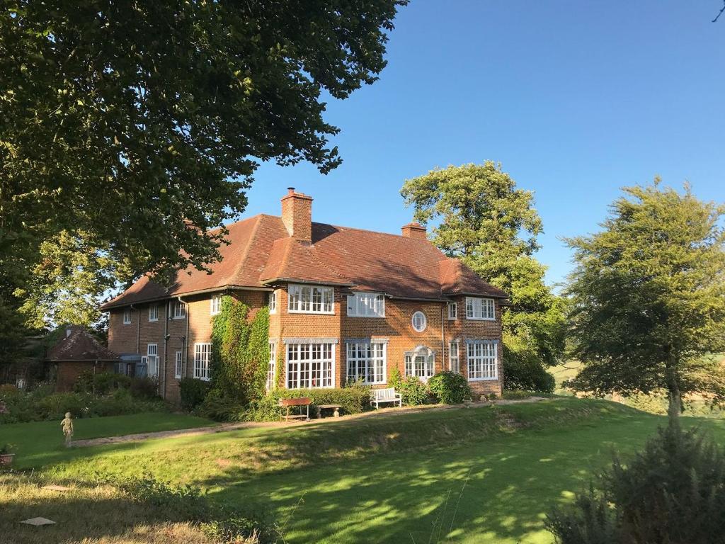 a large brick house on a grassy hill at Castle Hill House in Sidbury