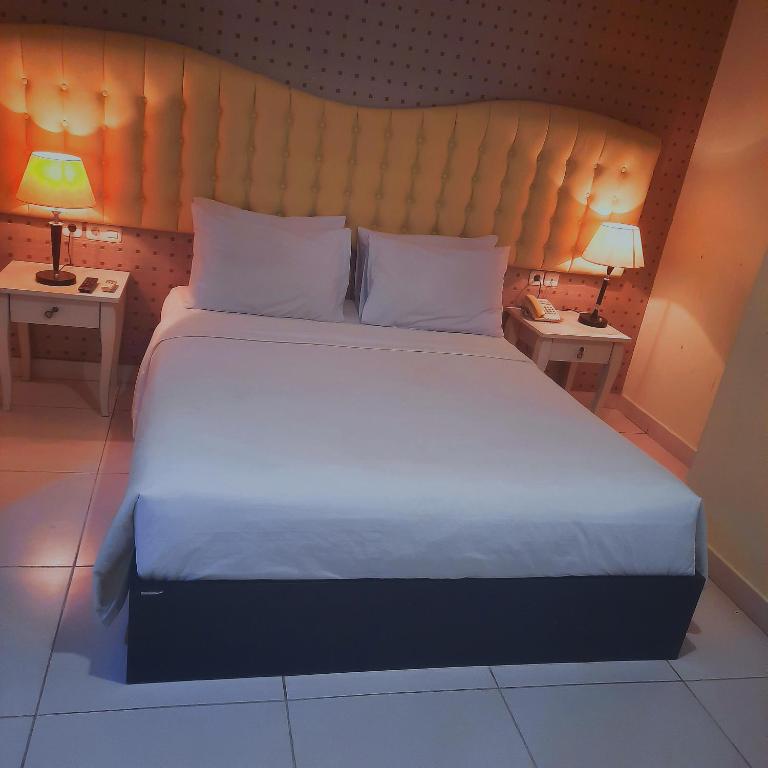 a bedroom with a large bed with two tables and two lamps at Anaya Hotel and Ballroom in Medan