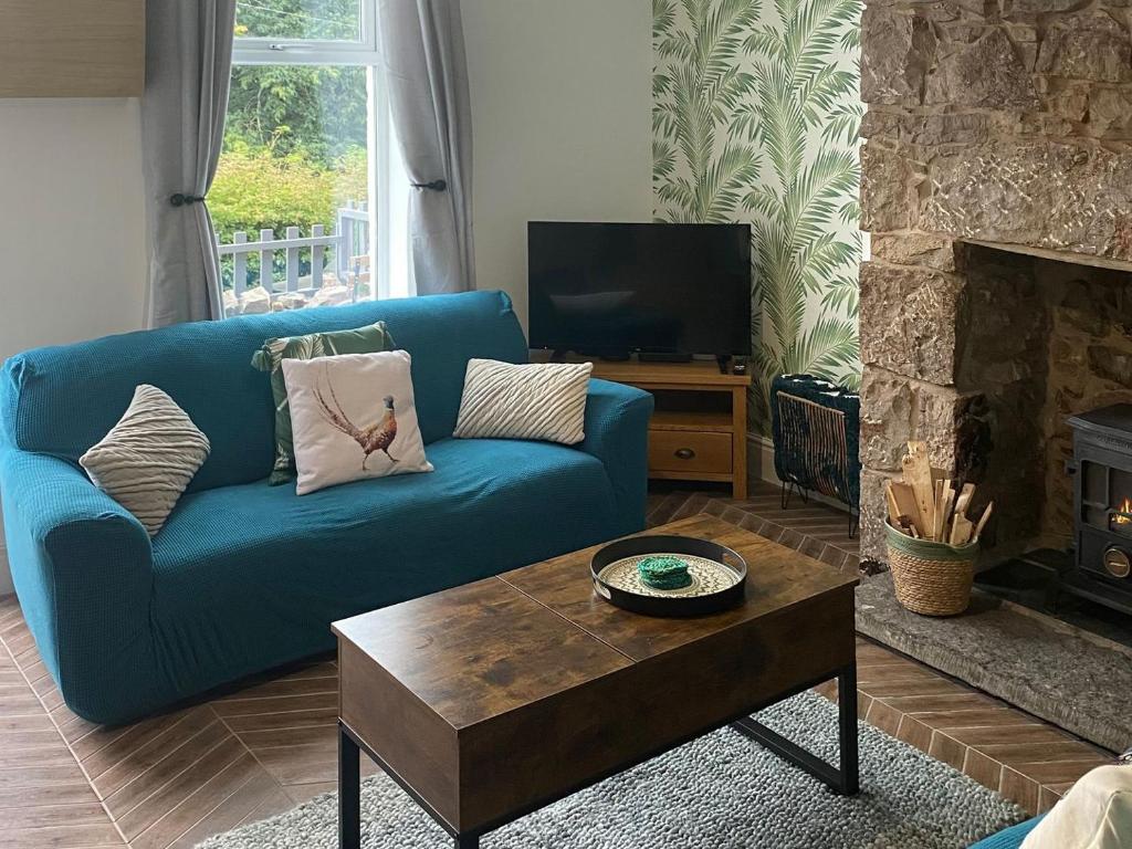 a living room with a blue couch and a fireplace at Quarrymans in Llysfaen
