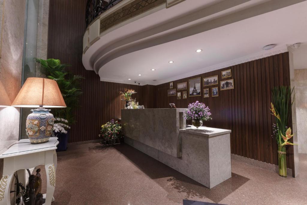 a lobby with a reception desk and flowers on the wall at Roseland Corp Hotel in Ho Chi Minh City