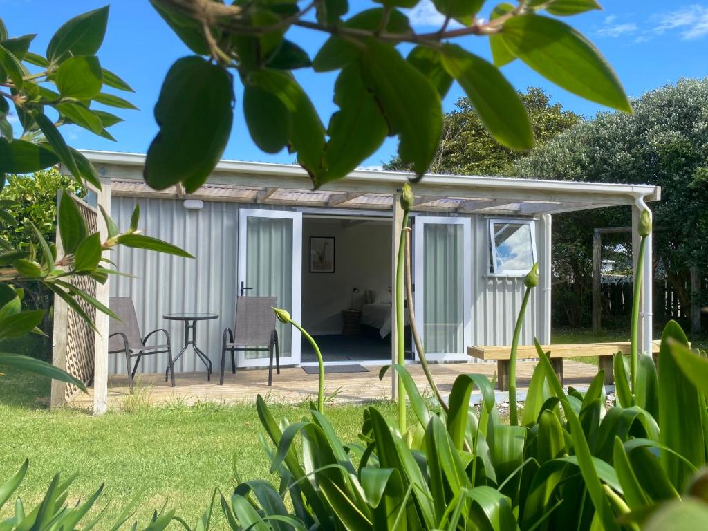 a cottage in the garden with a table and chairs at Beach Break Cabin - short walk to beach and cafes in Waihi Beach