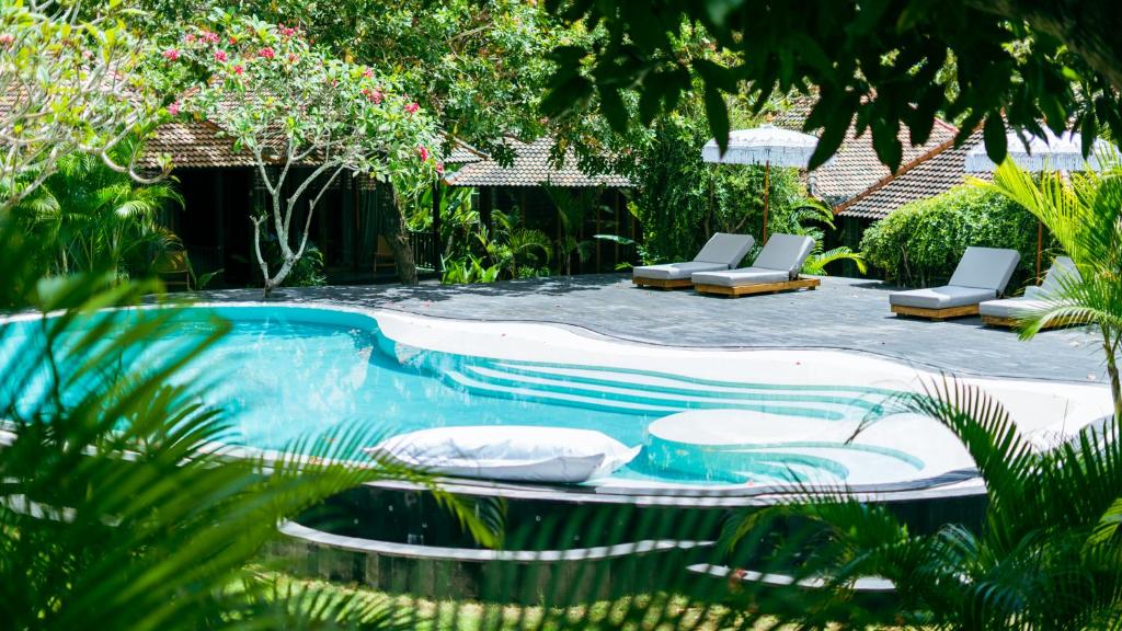 a swimming pool with lounge chairs in a garden at ONAYA Bali Resort - Adults Only in Uluwatu