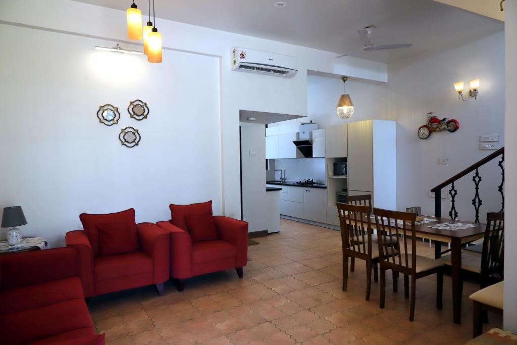 バーカにあるAgosto @Aansav Verde Fatrade Varca GOA 3 BR Villaのリビングルーム、キッチン(赤い椅子、テーブル付)