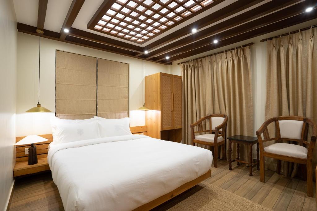 帕坦Karuna Hotel Patan Kathmandu的一间卧室，配有一张床、一张桌子和几把椅子