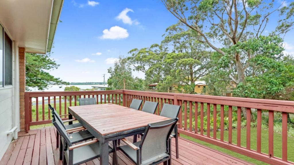 a wooden deck with a wooden table and chairs at 4 Kururma Crescent Hawks Nest in Hawks Nest
