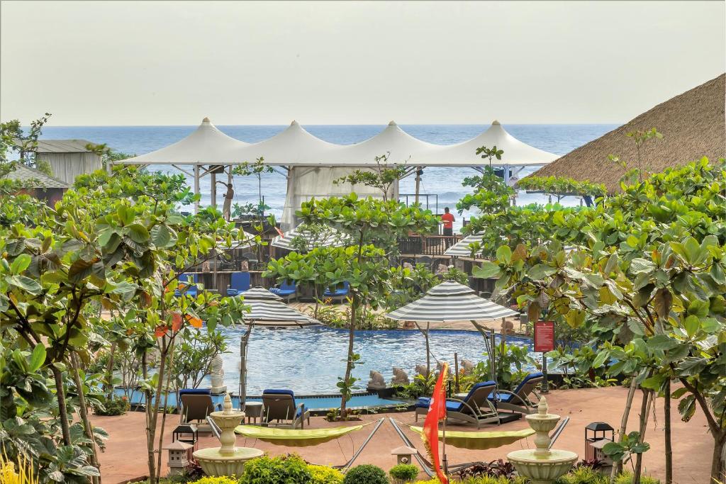 uma piscina num resort com cadeiras e guarda-sóis em Mayfair On Sea, Morjim Beach, Goa em Morjim