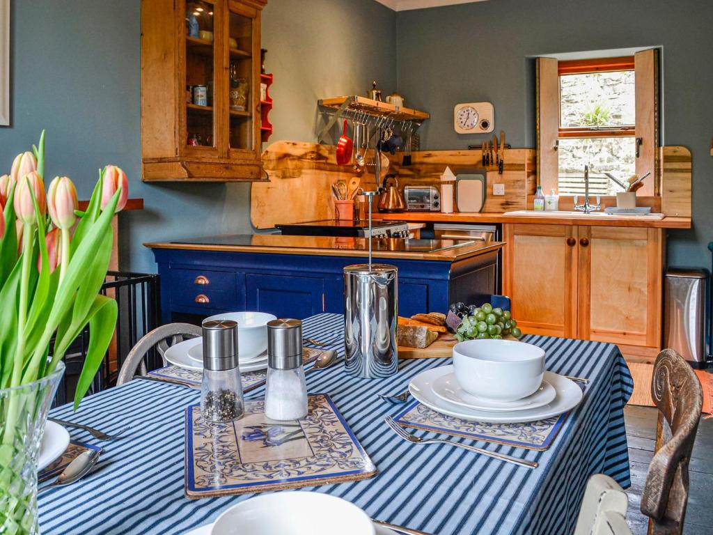 a kitchen with a table with a blue and white table cloth at Rosebank Cottage in Borgue