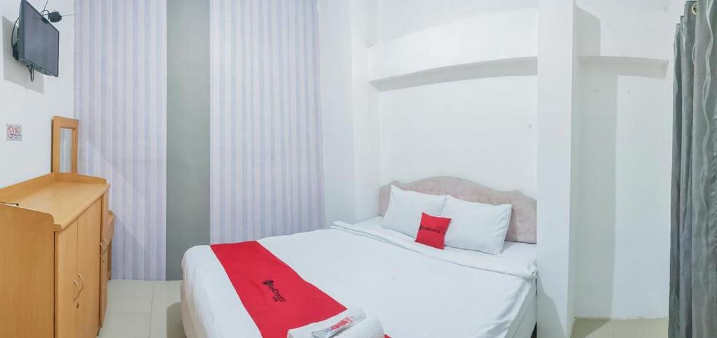 een slaapkamer met een wit bed met een rode deken erop bij RedDoorz Syariah at Jemursari Surabaya in Surabaya