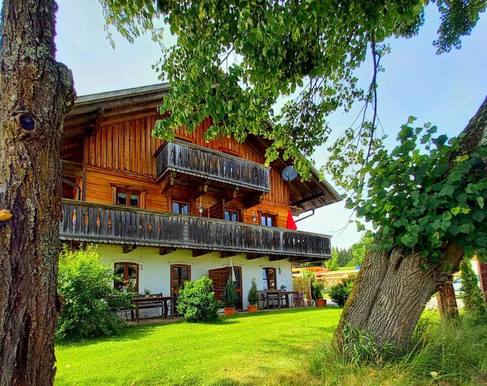 un gran edificio de madera con balcones en un patio verde en Landhaus Friedl, en Riedlhütte