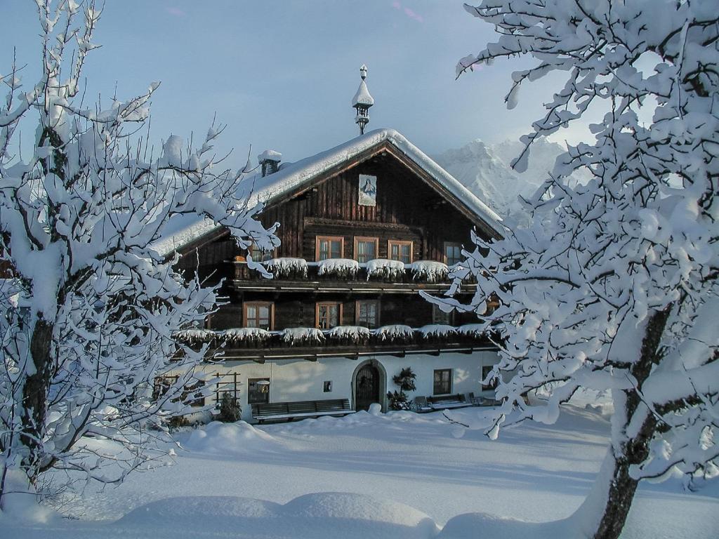 a building covered in snow with snow covered trees at Hinterburghof in Saalfelden am Steinernen Meer