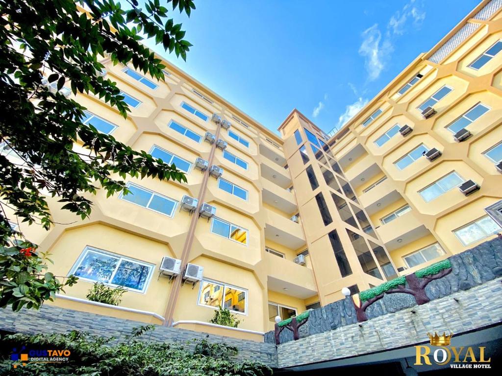 un gran edificio amarillo con ventanas. en Royal Village Hotel, en Dar es Salaam
