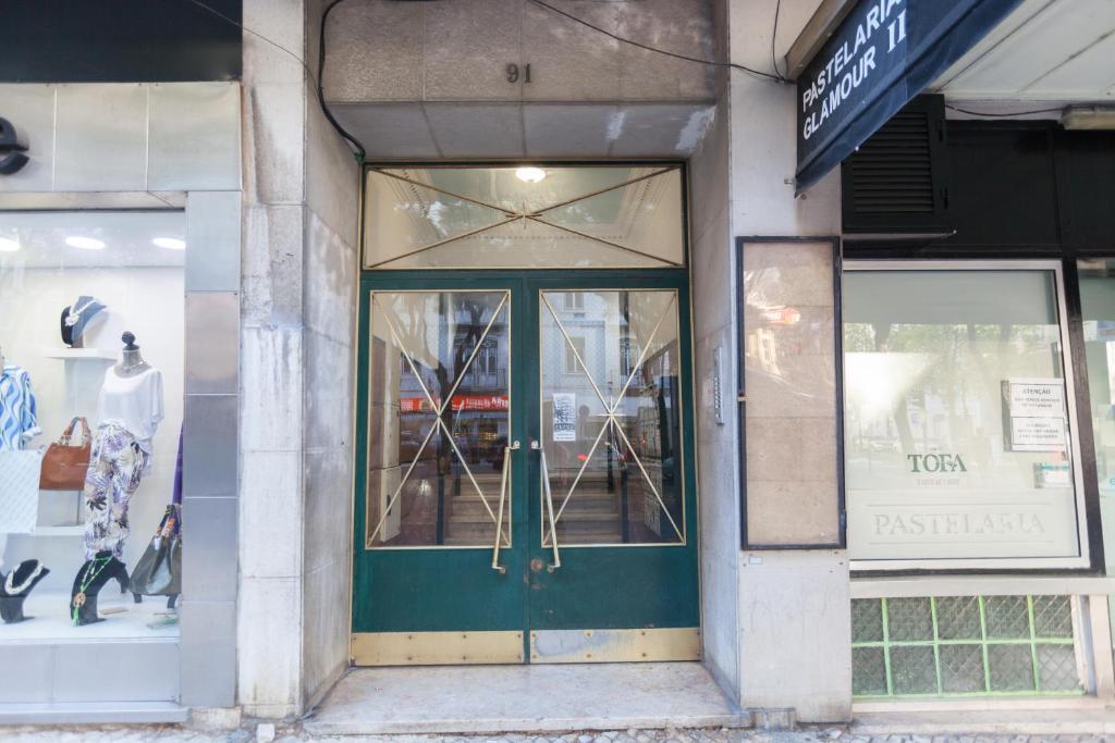 une façade de magasin avec une porte verte et des fenêtres dans l'établissement FLH Gulbenkian Apartment with Balcony, à Lisbonne