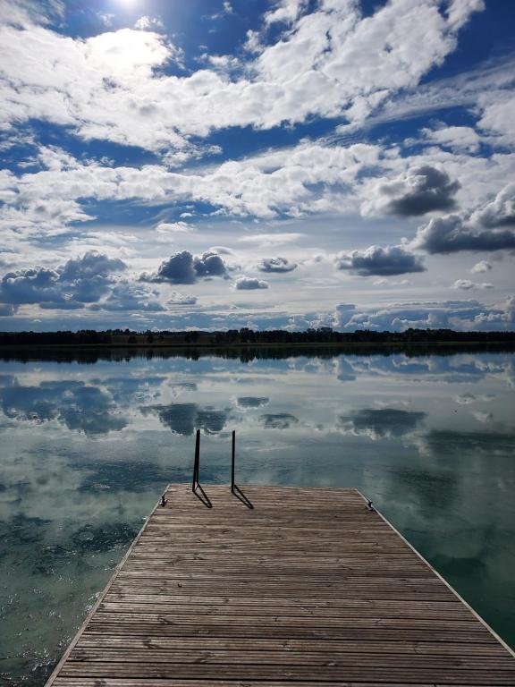 a dock on a body of water with a cloudy sky at Warmińska Przystań - dom całoroczny in Blanki
