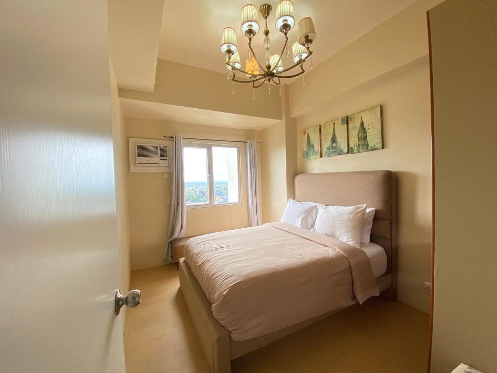 a bedroom with a bed with a chandelier and a window at Spacious 1 Bedroom Unit at Centrio Tower in Cagayan de Oro