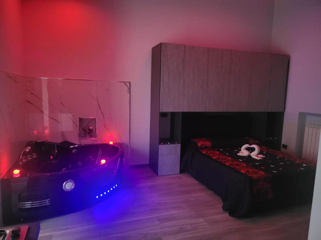 Zimmer mit einem Bett und einer Badewanne mit roten Lichtern in der Unterkunft Giovi's Apartments in Castellammare di Stabia