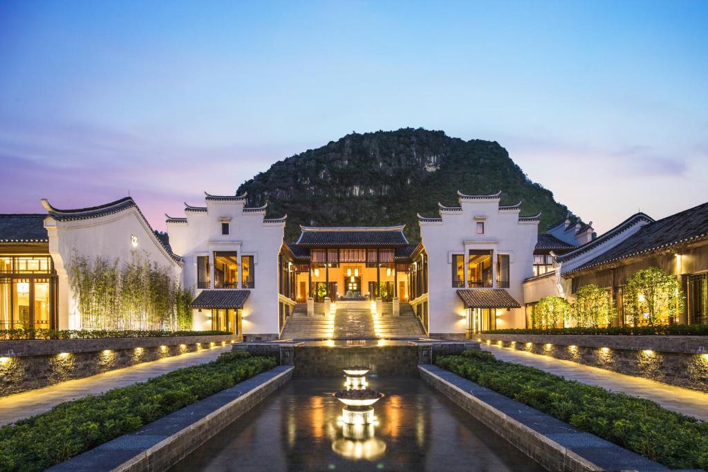 a house with a pond in front of a building at Banyan Tree Yangshuo in Yangshuo