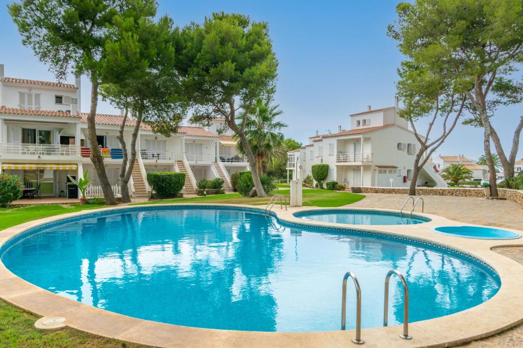 a swimming pool with trees and buildings in the background at Edisol 29 -Villa Pilar 2- in Port d'Addaia