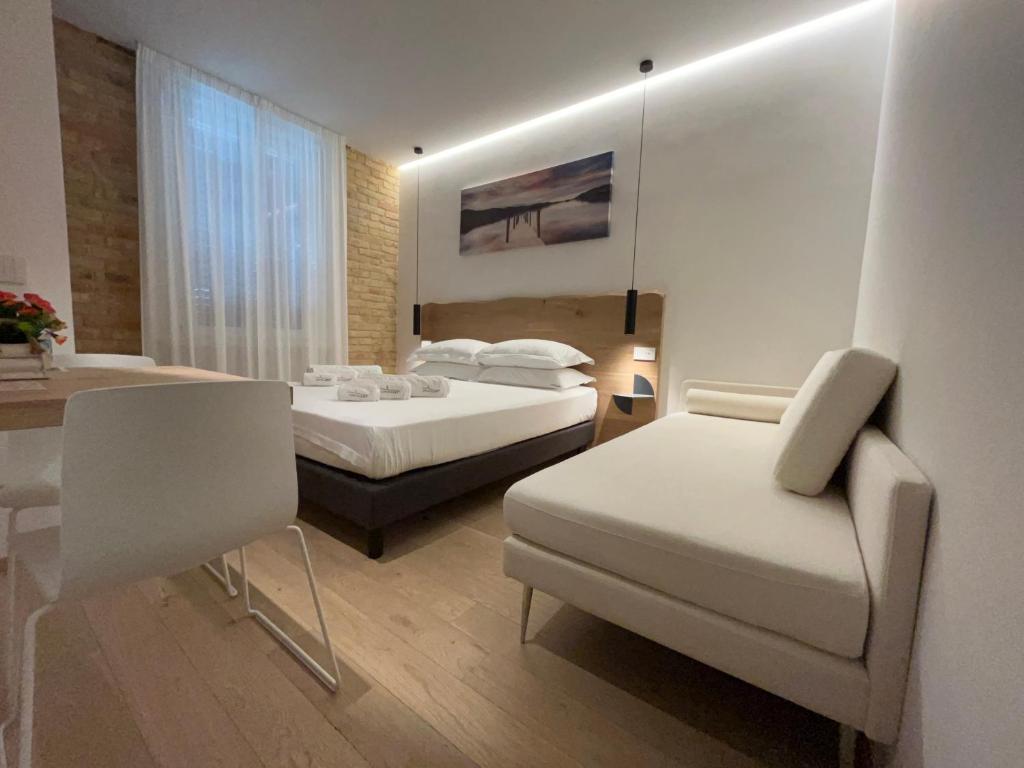 a bedroom with two beds and a chair and a table at Civitaloft Luxury Rooms in Civitanova Marche