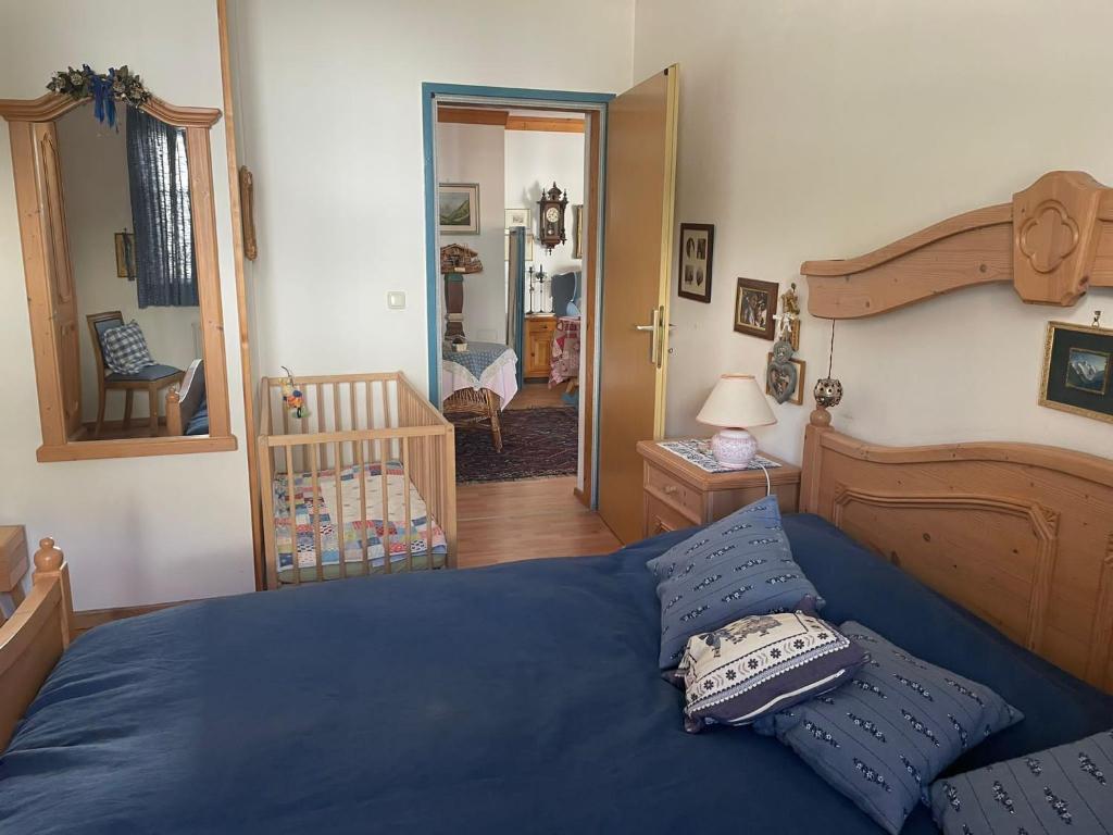 a bedroom with a bed with blue sheets and a crib at Bella Stubai in Fulpmes