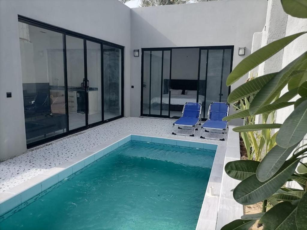 a swimming pool with two blue chairs in a house at شاليه اللويمي in Al Hofuf