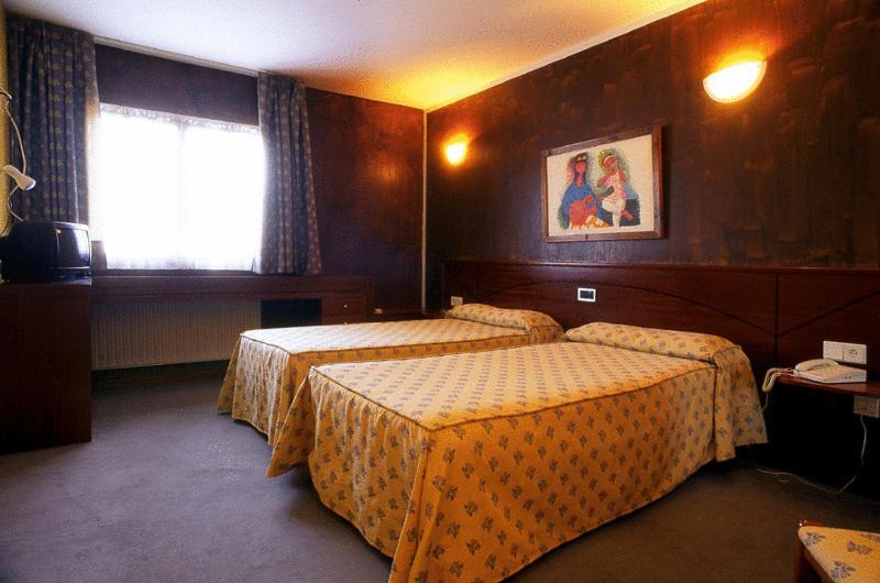 Habitación de hotel con 2 camas y ventana en Hotel Villa De Nava en Nava