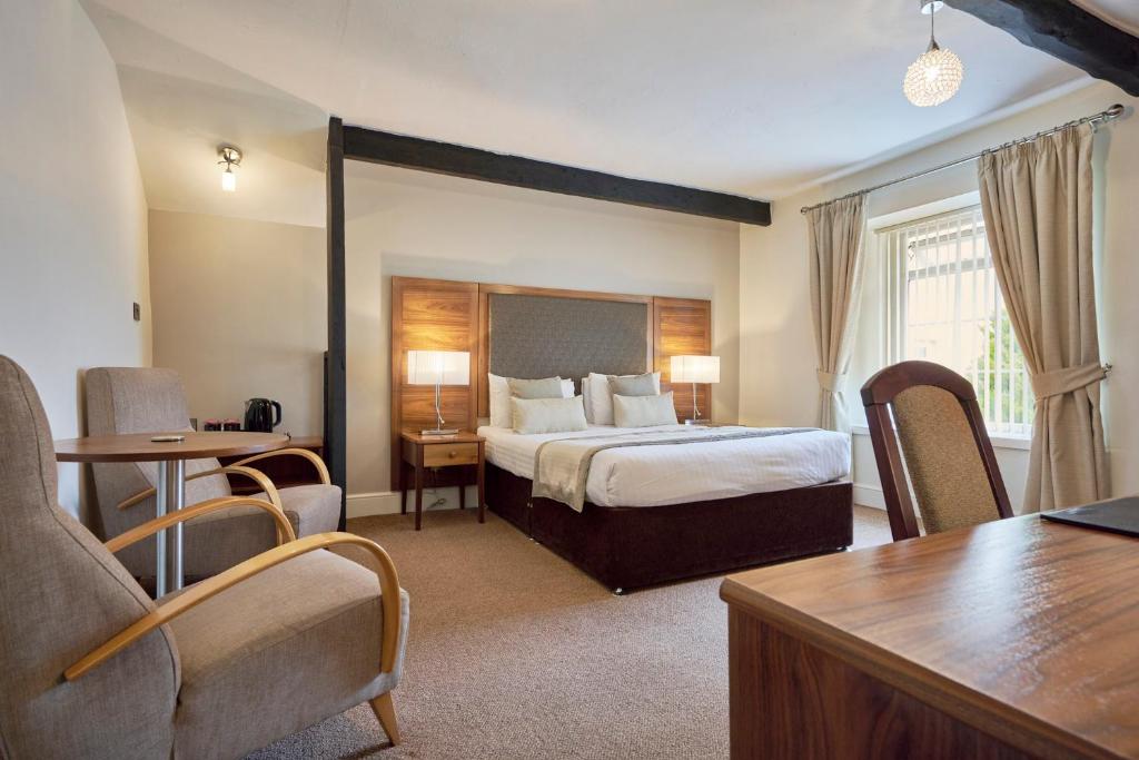 The Old Ginn House Inn في Great Clifton: غرفة فندقية بسرير وطاولة وكراسي