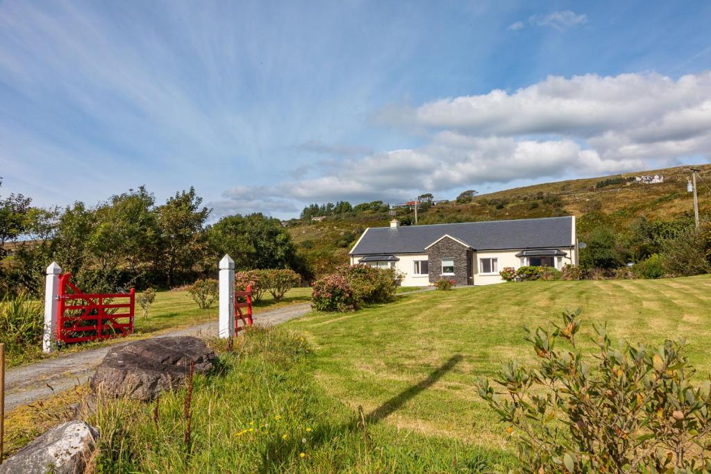 a house on a hill with a grass yard at Church Island View Holiday Home in Waterville