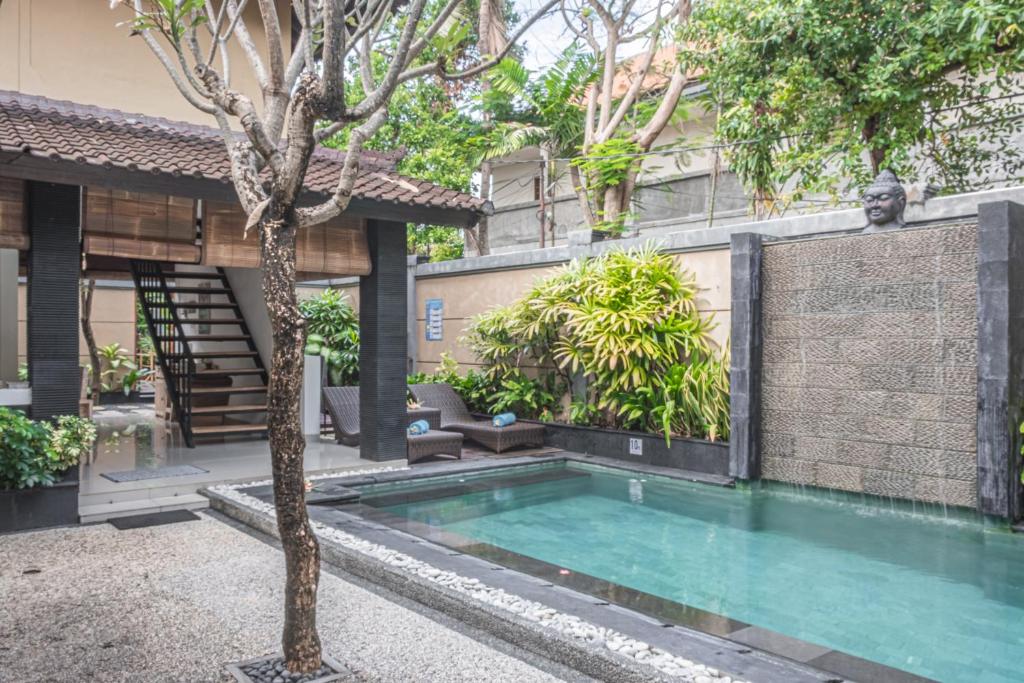 una piscina frente a una casa con un árbol en Villa Karma Legian, en Legian