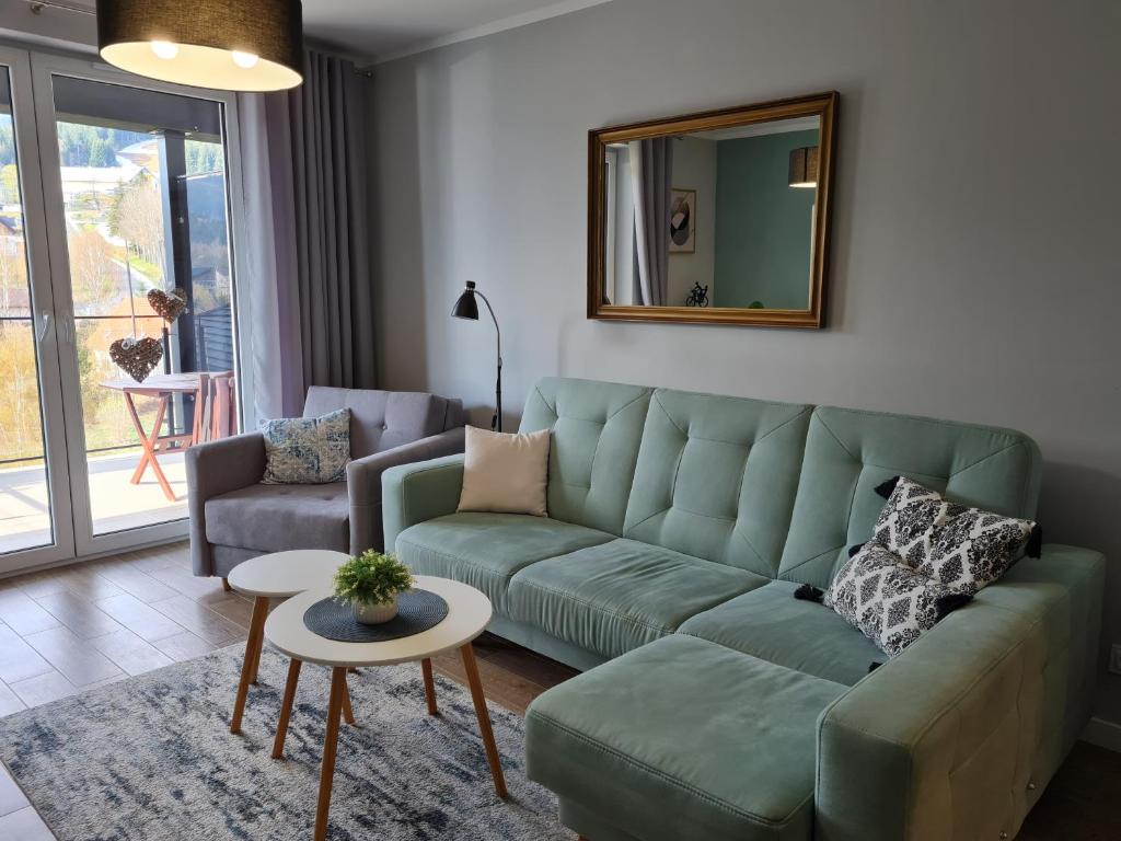 a living room with a green couch and a mirror at PIAM Apartamenty in Świeradów-Zdrój