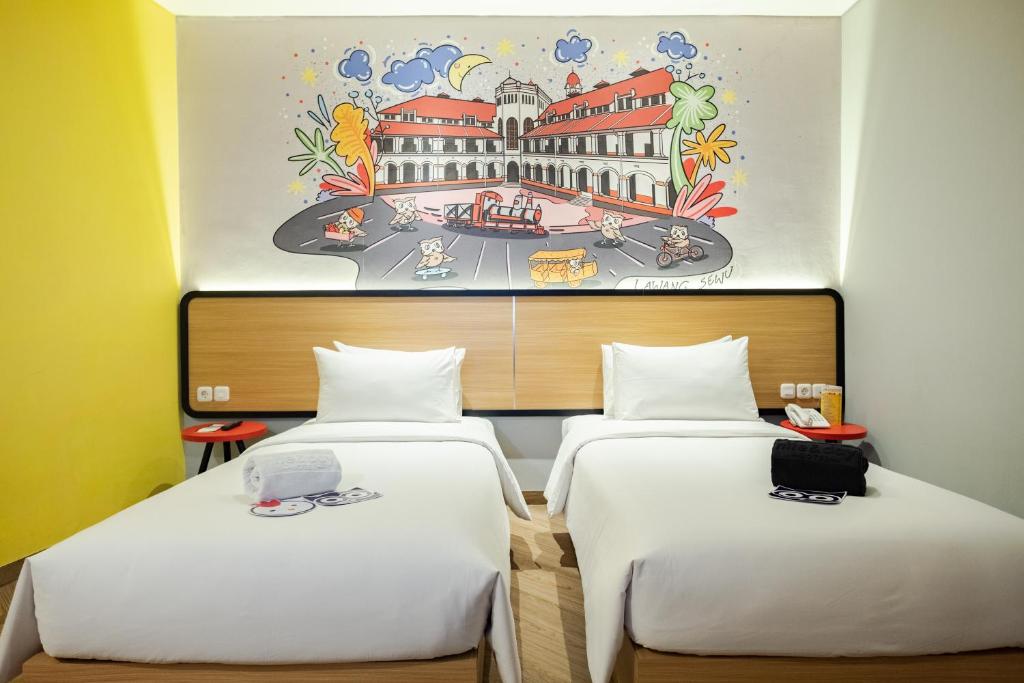 two beds in a room with a painting on the wall at Nite & Day Semarang - Candi in Semarang