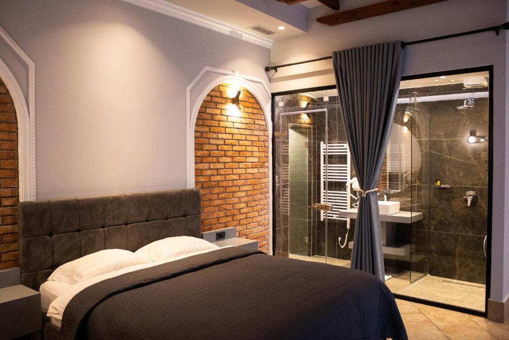 um quarto com uma cama e uma cabina de duche em vidro em Venis Hotel em Tirana
