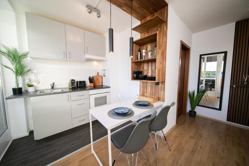a kitchen with white cabinets and a white table and chairs at Studio WHITE - Central - Balcony - Fair - Kitchen in Neuss