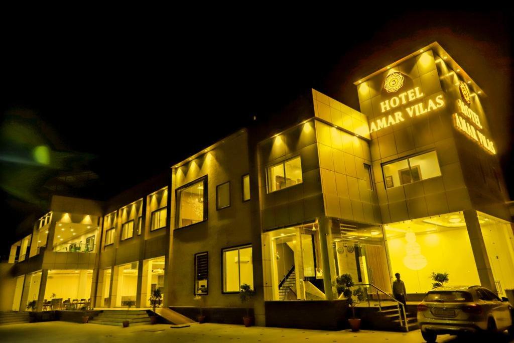 a man standing in front of a building at night at Hotel Amar Vilas & Resort in Bharatpur