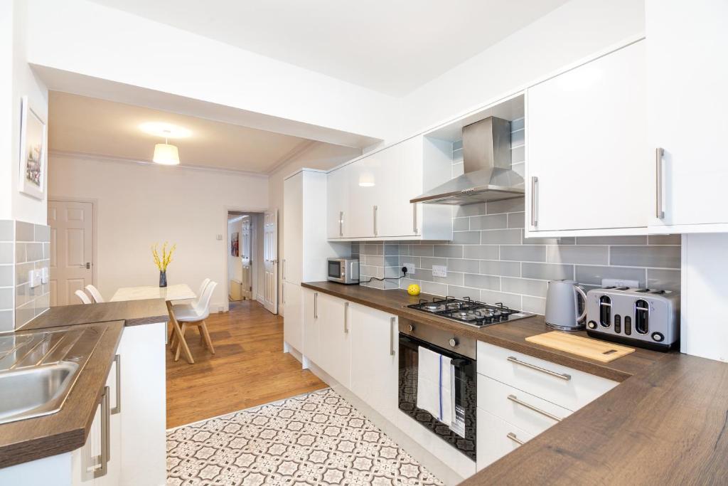 a kitchen with white cabinets and a counter top at 4 bedroom house, 5 double beds and free parking. in Beeston