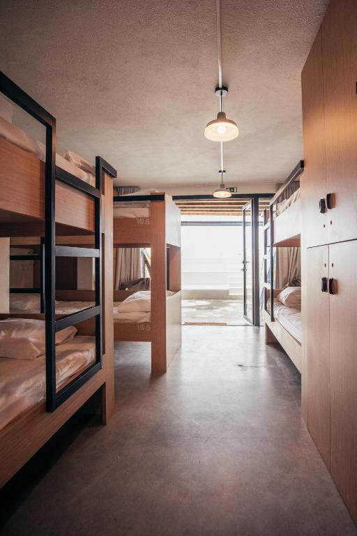 a room with several bunk beds and a hallway at MUTE Hostel Porto Covo in Porto Covo