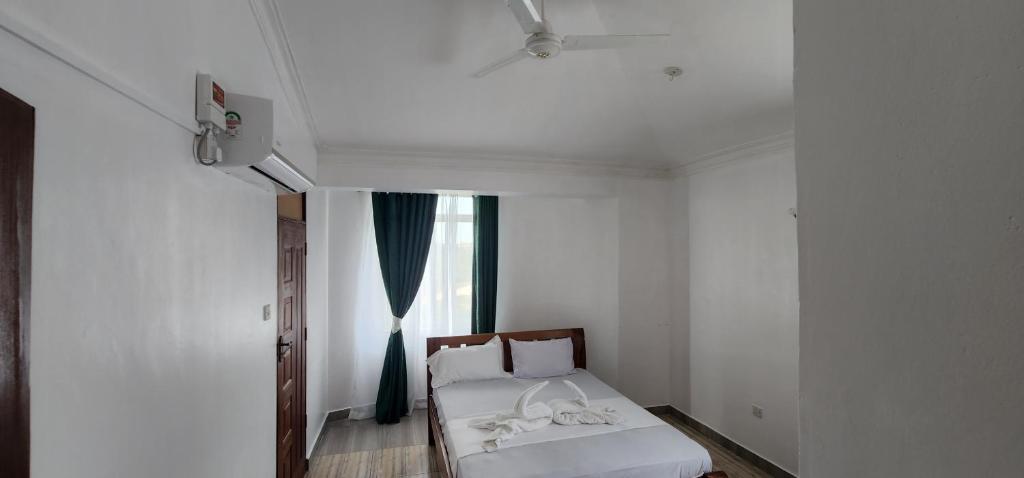 a white room with a bed and a window at Pride in Homestay 2 in Mombasa